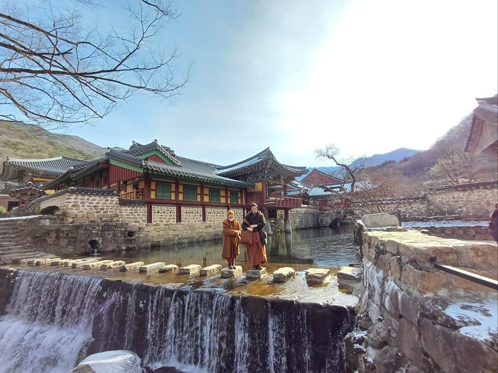 Sangha Treasure Temple stepping stones across the river with Ayya Sucitta and Ayya Niyyanika standing on the stones above a waterfall